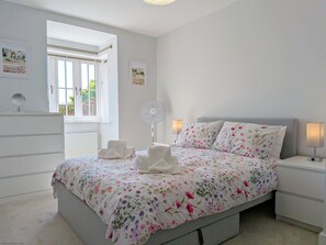 Un dormitorio con una cama, mesitas de noche, una ventana y un radiador.