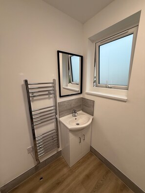 Ett badrum med en inbyggd tvättställ, en handduksställning, en spegel och ett fönster.