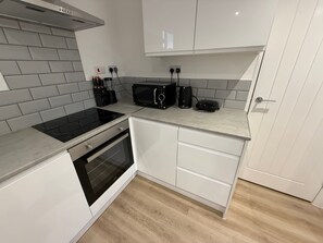 Ett modernt kök med en inbyggd spis, mikrovågsugn och kaffebryggare.