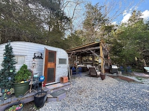 A mobile home with a covered porch, a small Christmas tree, and outdoor seating. - Glamping, Goats & Pool Mountainside NEAR Va Tech, RU, AT & I81, pet friendly (Blacksburg)