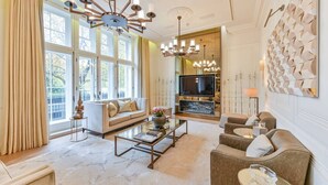 Een ruime woonkamer met een bank, fauteuils, een salontafel en een televisie.