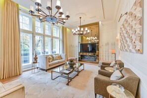 Ein großzügiges Wohnzimmer mit einer Couch, Sesseln, einem Couchtisch und einem Fernseher.