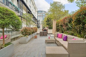 Ein Innenhof mit Sitzbereichen, Pflanzkübeln und Blick auf ein modernes Gebäude im Hintergrund.