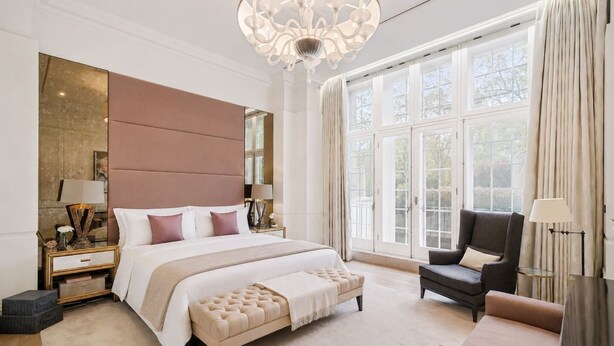 Een ruime slaapkamer met een groot bed, een zithoek en uitzicht op de omgeving door grote ramen.