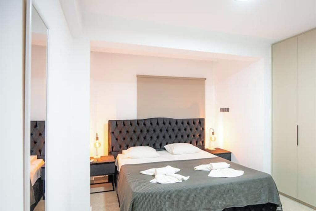 A bedroom with a large bed, bedside tables, a wardrobe, and a window with a blind.