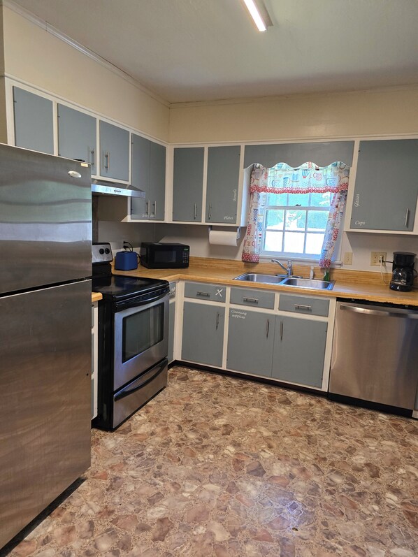 Una cocina equipada con refrigerador, estufa, microondas y lavaplatos.