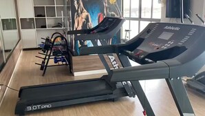 Une salle de sport équipée de tapis de course, d’appareils de musculation et d’un grand miroir.