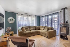 A modern living room with a sectional sofa, a fireplace, and a dining area. - 3-Bedroom House with Pool (Villelongue-dels-Monts)
