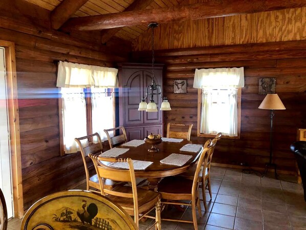 A wooden dining room with a round table, chairs, and a chandelier.