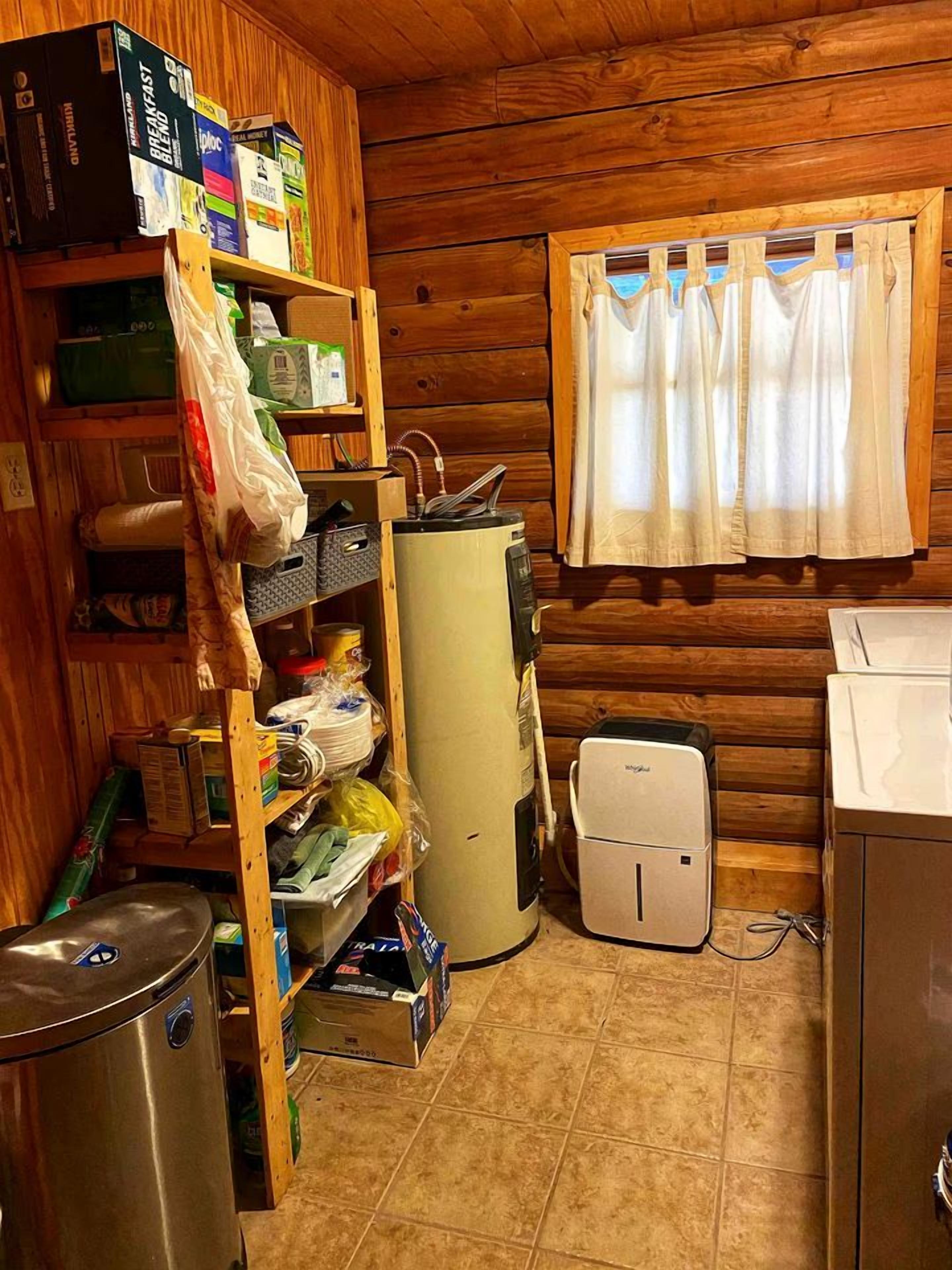 Ett kompakt kök med träväggar, ett kylskåp, en mikrovågsugn, en diskho och ett fönster med gardiner.