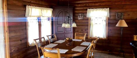 Un comedor de madera con una mesa redonda, sillas y una araña.