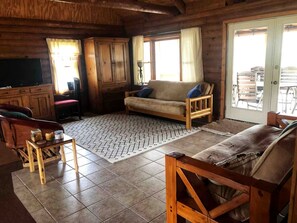 A wooden interior with a sofa, a wooden chair, a small table, and a cabinet. - Side by Side Cabins on a Texas Ranch, Perfect for a Family Glamping Getaway from San Antonio (Mico)