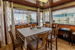 A dining area with a table set for four, wooden chairs, a bench, and a view through the window. - Vintage-Inspired Haven with Bright Interiors & Relaxing Outdoor Spaces in Bacliff, Texas (Bacliff)
