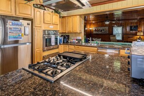 Eine Küche mit Granit Arbeitsplatten, Edelstahlgeräten, Holzschränken, einem Gasherd und einem eingebauten Backofen.