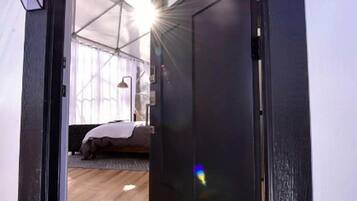 Una puerta que da a una habitación con una cama, una lámpara y una ventana.