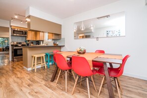 A modern kitchen with stainless steel appliances, a dining area with red chairs and a wooden table, and a large mirror on the wall. - Vancouver home, 10 minute drive to downtown. Close to Skytrain, parking included (Vancouver)