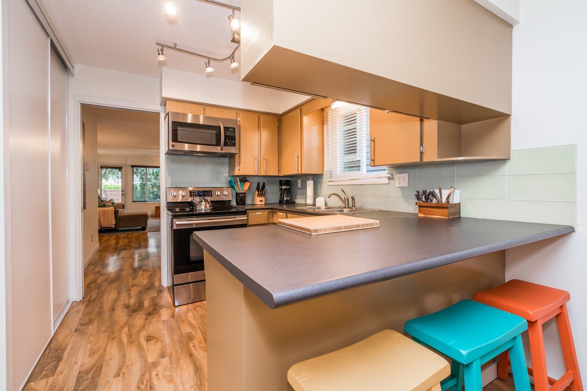 Een moderne keuken met roestvrijstalen apparatuur, een groot eiland en houten vloeren.