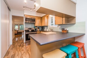 A modern kitchen with stainless steel appliances, a large island, and wooden flooring. - Vancouver home, 10 minute drive to downtown. Close to Skytrain, parking included (Vancouver)