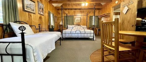A room with two beds, a wooden dining table, and a fireplace.