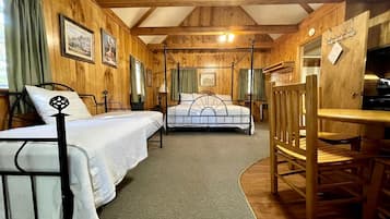 A room with two beds, a wooden dining table, and a fireplace.