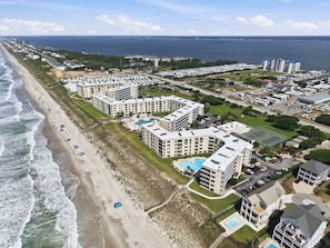 Ein Küstenhotel mit mehreren Gebäuden, einem Strand und einem großen Parkplatz.