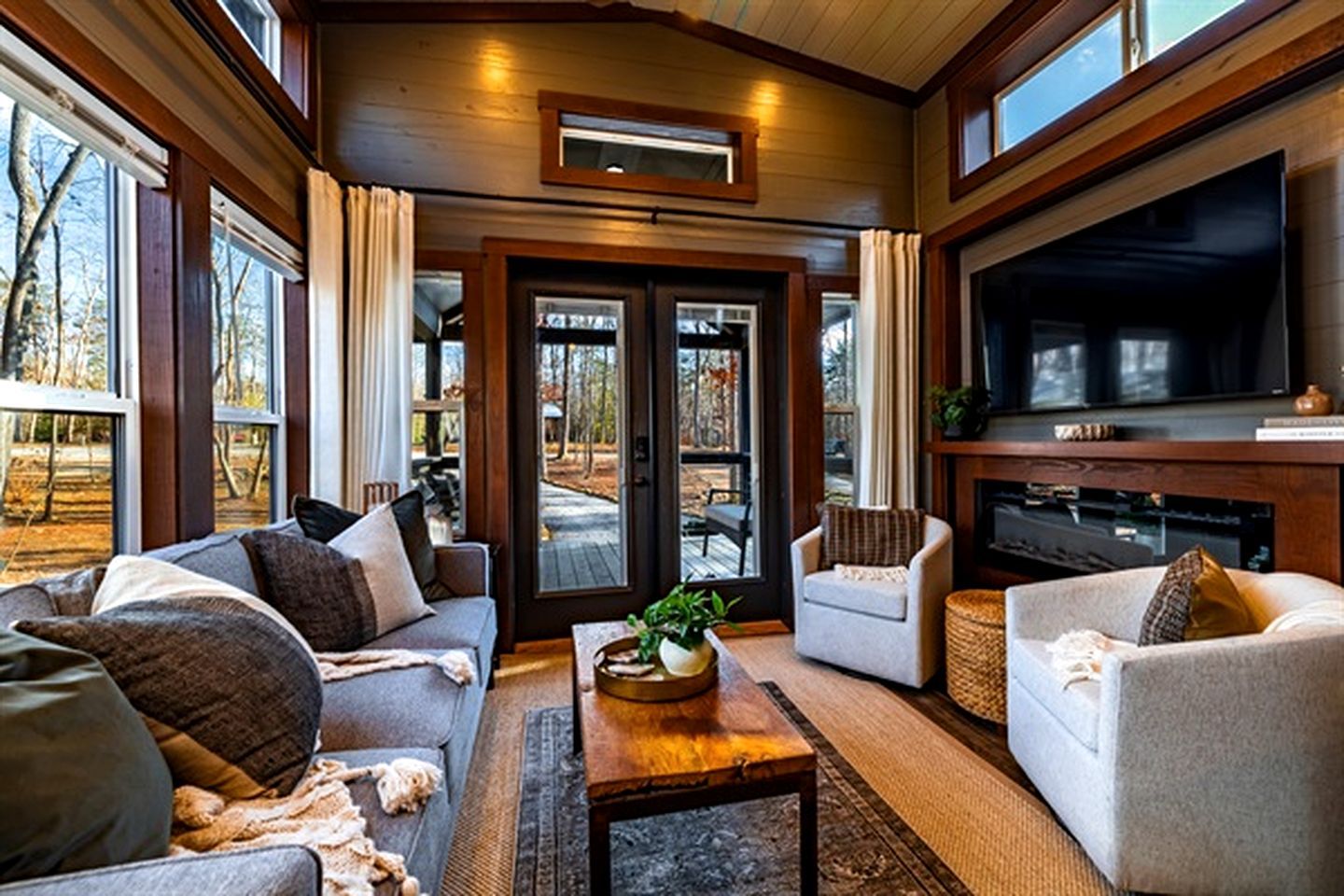 A cozy living room with a sofa, armchairs, a coffee table, and a television.