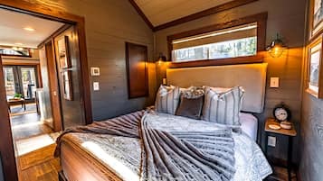 A bedroom with a bed, bedside tables, a window, and a door leading to an outdoor area.