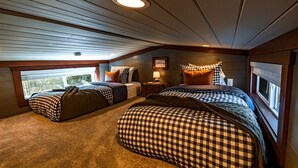 Ein Schlafzimmer mit zwei Betten, einem Fenster, einer Lampe und einer Deckenleuchte.