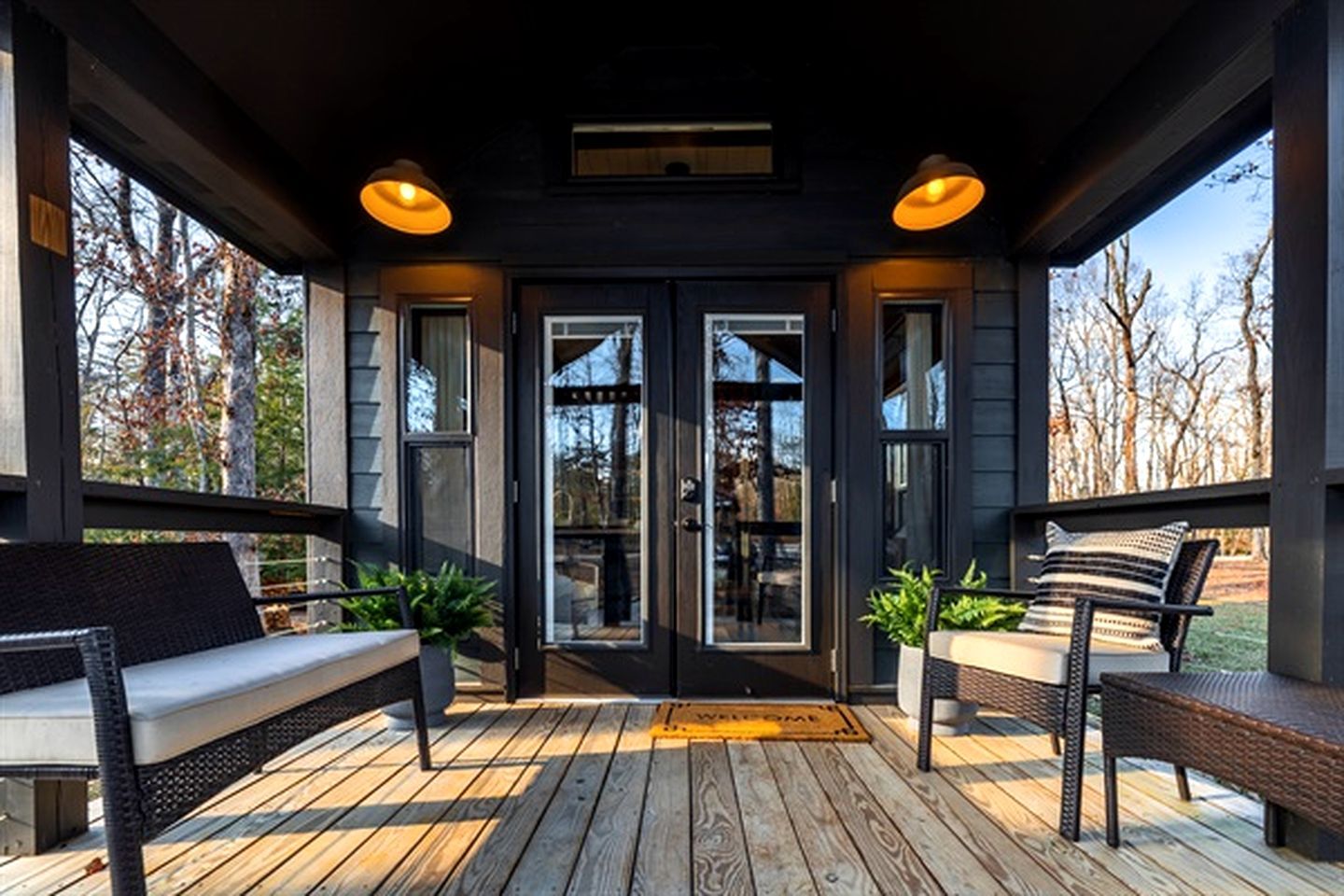 A covered porch with a bench, a door with glass panels, and a view of trees.