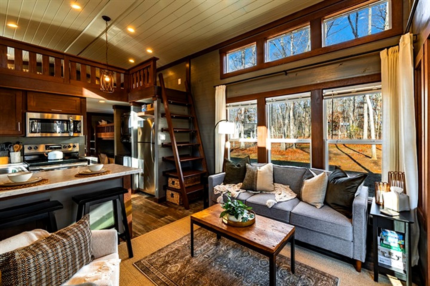 A cozy living room with a sofa, coffee table, and a view of the outdoors through large windows.