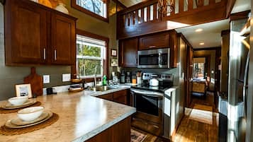A kitchen with wooden cabinets, a large island, stainless steel appliances, and a view through the window.