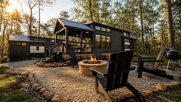 A modern outdoor living area with a fire pit, seating, and a barbecue grill.