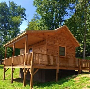 A wooden cabin with a porch, a window, and a door.