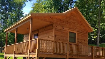 A wooden cabin with a porch, a window, and a door.