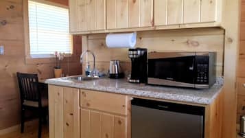 A compact kitchen with wooden cabinets, a sink, a coffee maker, a microwave, and a dishwasher.