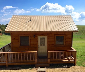 A wooden cabin with a metal roof, a front door, and two windows. - Charming Cabin Rental with Blue Ridge Mountain Views in Purlear, North Carolina (Purlear)