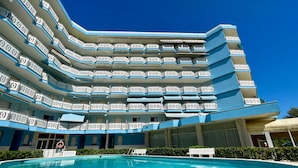 A multi-story hotel with a pool in the foreground. - Cozy Modern Studio With Pool Access (Caorle)