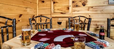 Un interior de madera con una mesa de póker, sillas y fichas de juego.
