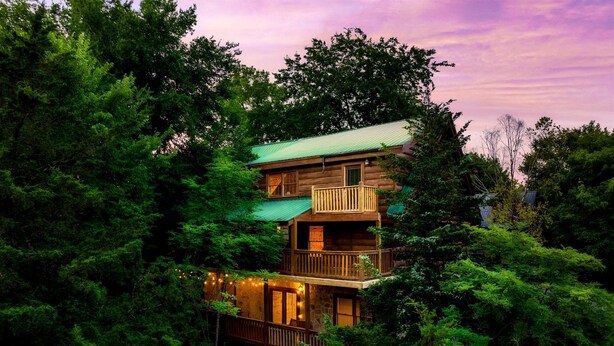 A multi-story log cabin with balconies, surrounded by dense forest. - Spectacular Cabin Surrounded by Trees in Pigeon Forge, Tennessee (Pigeon Forge)