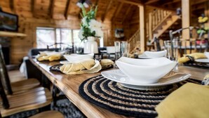 A wooden dining table with white bowls and plates, a vase with flowers, and a staircase in the background. - Spectacular Cabin Surrounded by Trees in Pigeon Forge, Tennessee (Pigeon Forge)