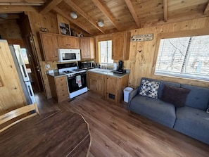 A cabin interior with a kitchen, dining area, and a sofa.