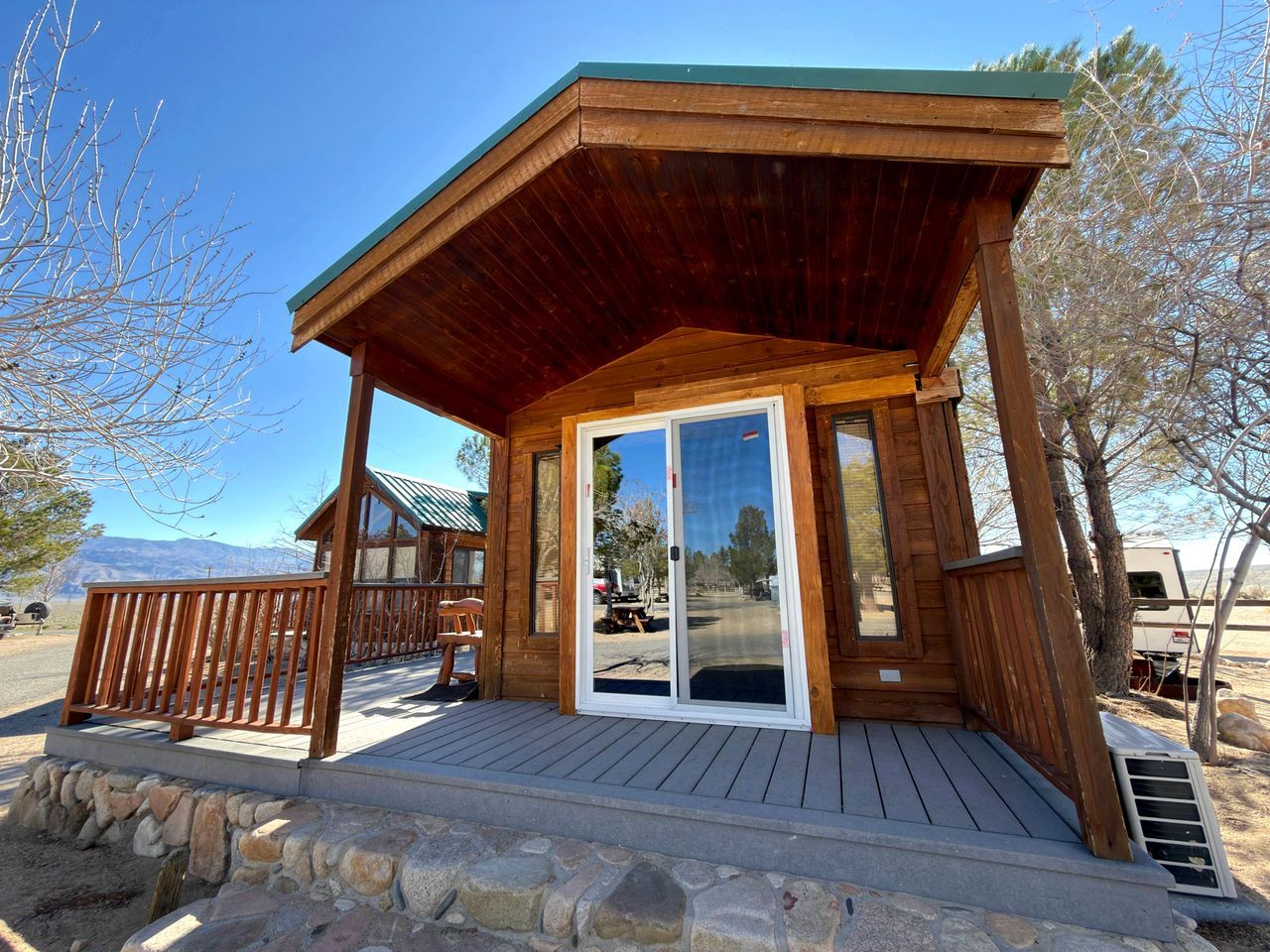 A wooden cabin with a covered porch and a sliding glass door.