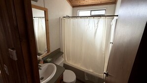 Ein Badezimmer mit Holzboden, einer Badewanne, einer Toilette und einem Waschbecken.