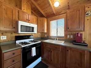 A kitchen with wooden cabinets, a gas stove, a microwave, a sink, and a coffee maker.