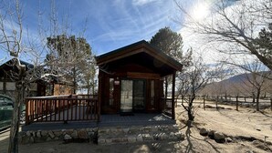 Eine Holzhütte mit Veranda, Steinstufen und freiem Blick auf die umliegende Landschaft.