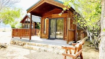 A wooden cabin with a porch, stone pathway, and wooden benches.