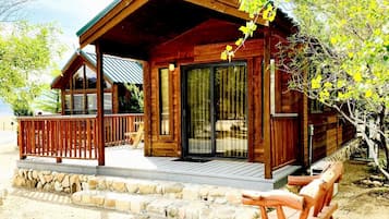 A wooden cabin with a porch, stone steps, and a bench.