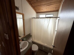 Un baño con techo de madera, una bañera, un inodoro y un lavabo.
