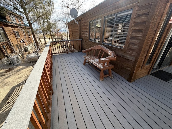 A wooden deck with a bench, a satellite dish, and a building with large windows.