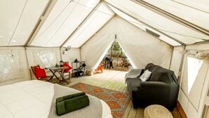 A tent with a bed, a sofa, a small table, and a chair.